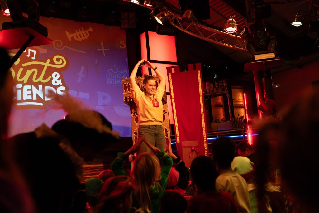 Presentatrice doet een dansje op het podium tijdens de Sint & Friends sinterklaasshow.
